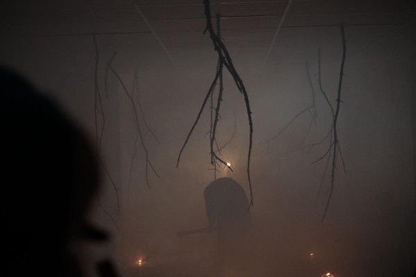 A foggy room with candles and branches.