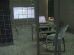 A desk, computer and chair behind a cage.