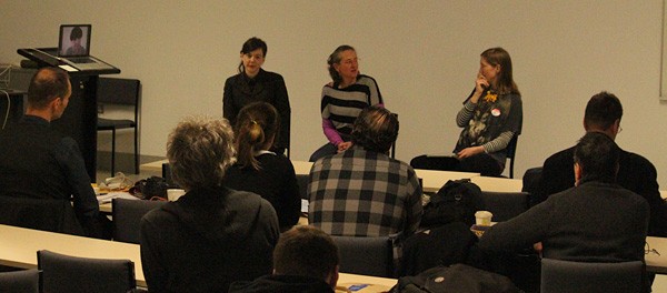 An audience listening to a panel of three people.